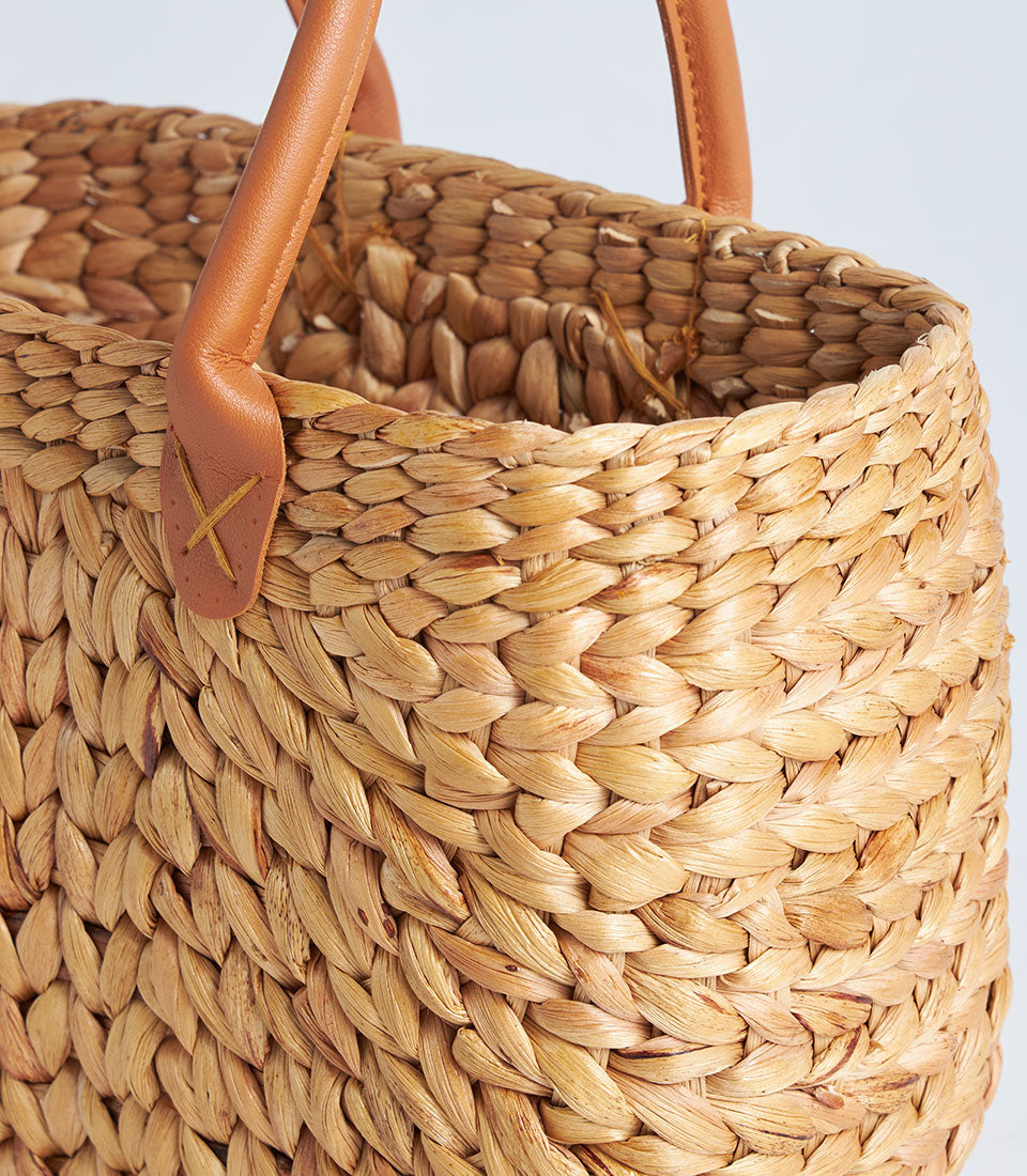 Natural woven straw basket with tan leather handles, artisan gift hamper design