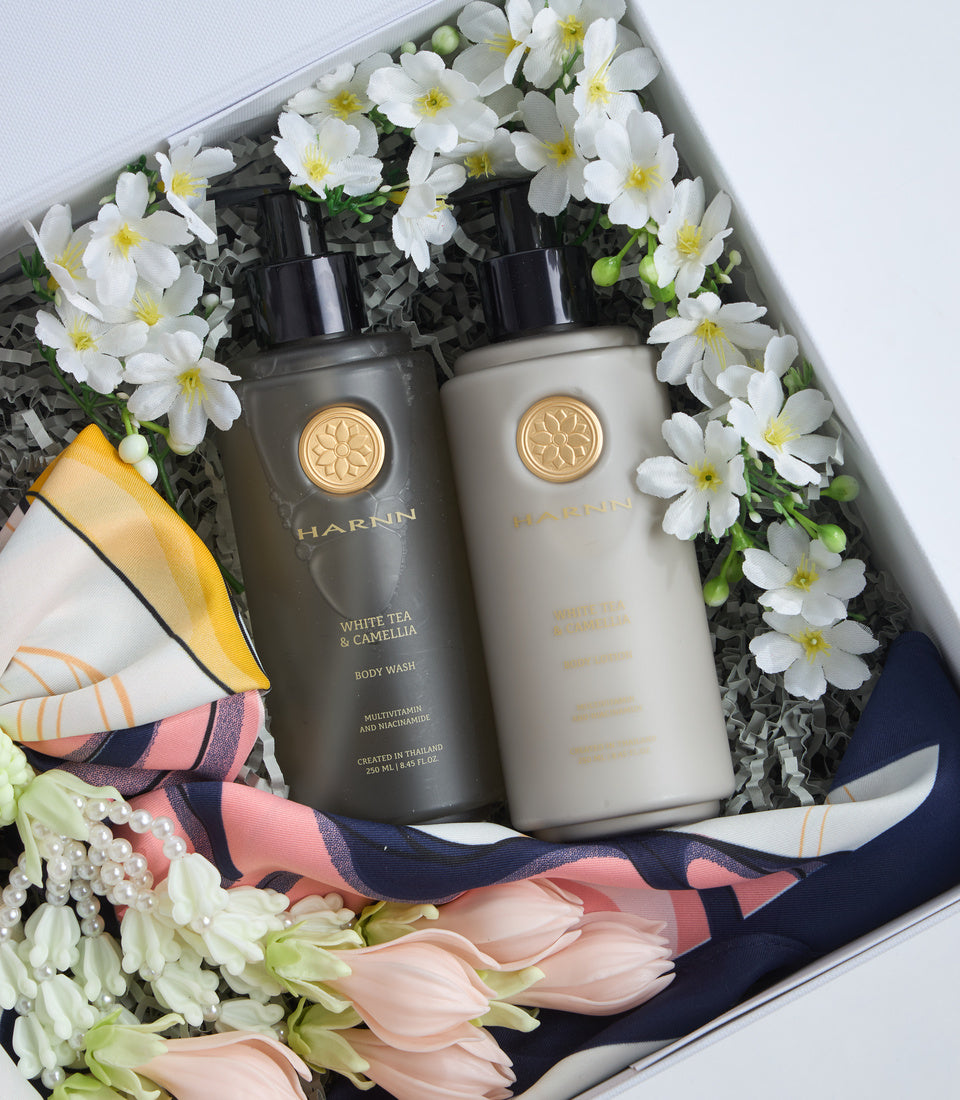 # Alt Text

Luxury spa gift set featuring two HARNN White Tea & Camellia products in dark and cream bottles with gold seals, surrounded by white daisies, pink tulips, and decorative ribbons in a white box.