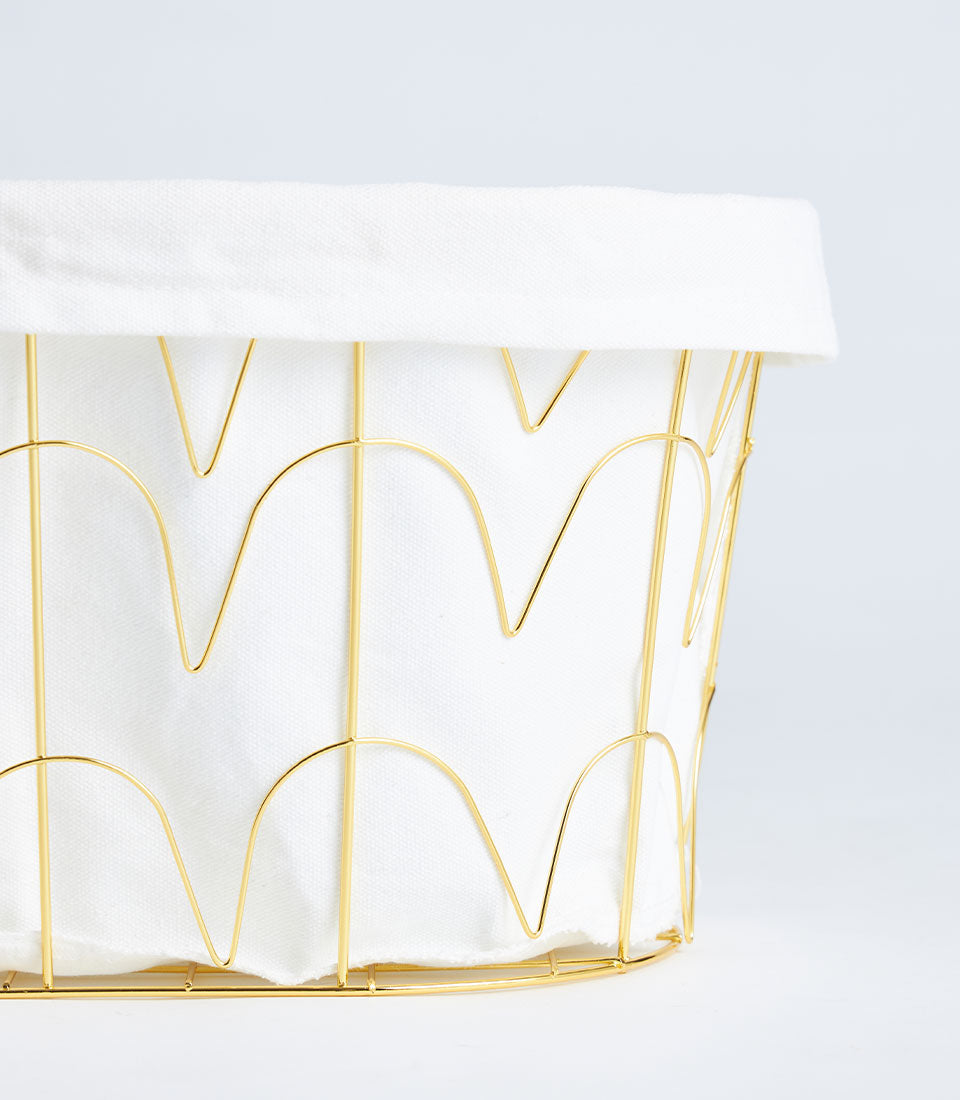 Gold metal wire basket with white fabric lining and decorative geometric pattern