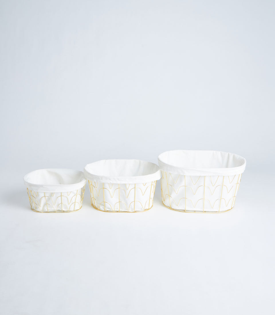 Gold metal frame storage baskets with white fabric linings, three sizes