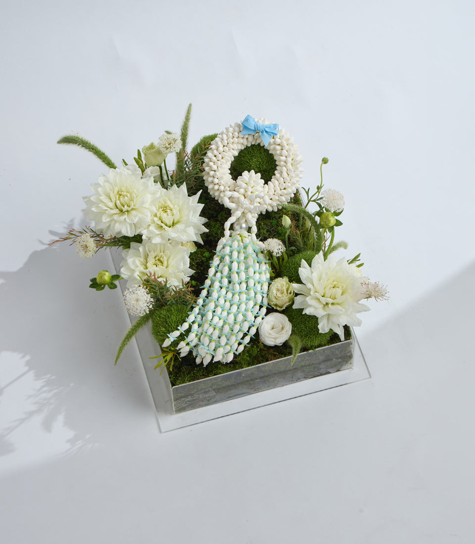 White and blue floral arrangement featuring dahlias, roses, moss ball, and beaded decorative elements in a gray wooden box.