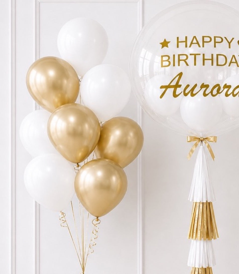 Elegant birthday decoration set featuring gold and white balloons with a clear bubble balloon, gold star, and white tassel garland with gold accents.