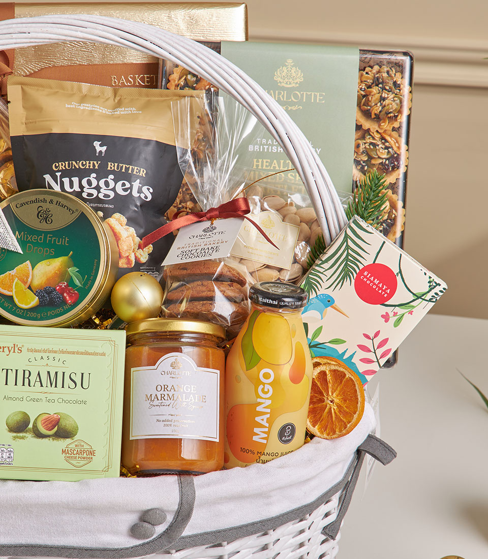 Luxury new year gourmet gift hamper with coconut roll, chocolate, mixed nuts and artisan treats in white wicker basket