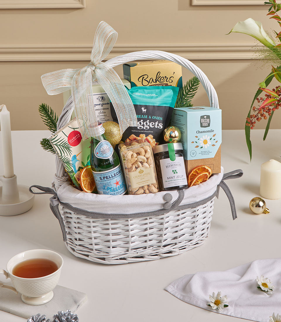 Luxury white wicker gift hamper with espresso coffee, cashews, sparkling water and gourmet snacks for New Year