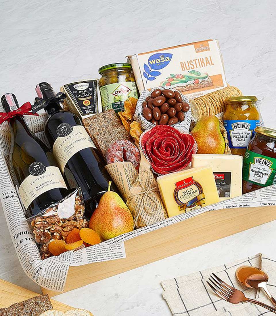 Premium wine and gourmet pairing gift basket with red and white wines, aged brie, olives, and artisan snacks