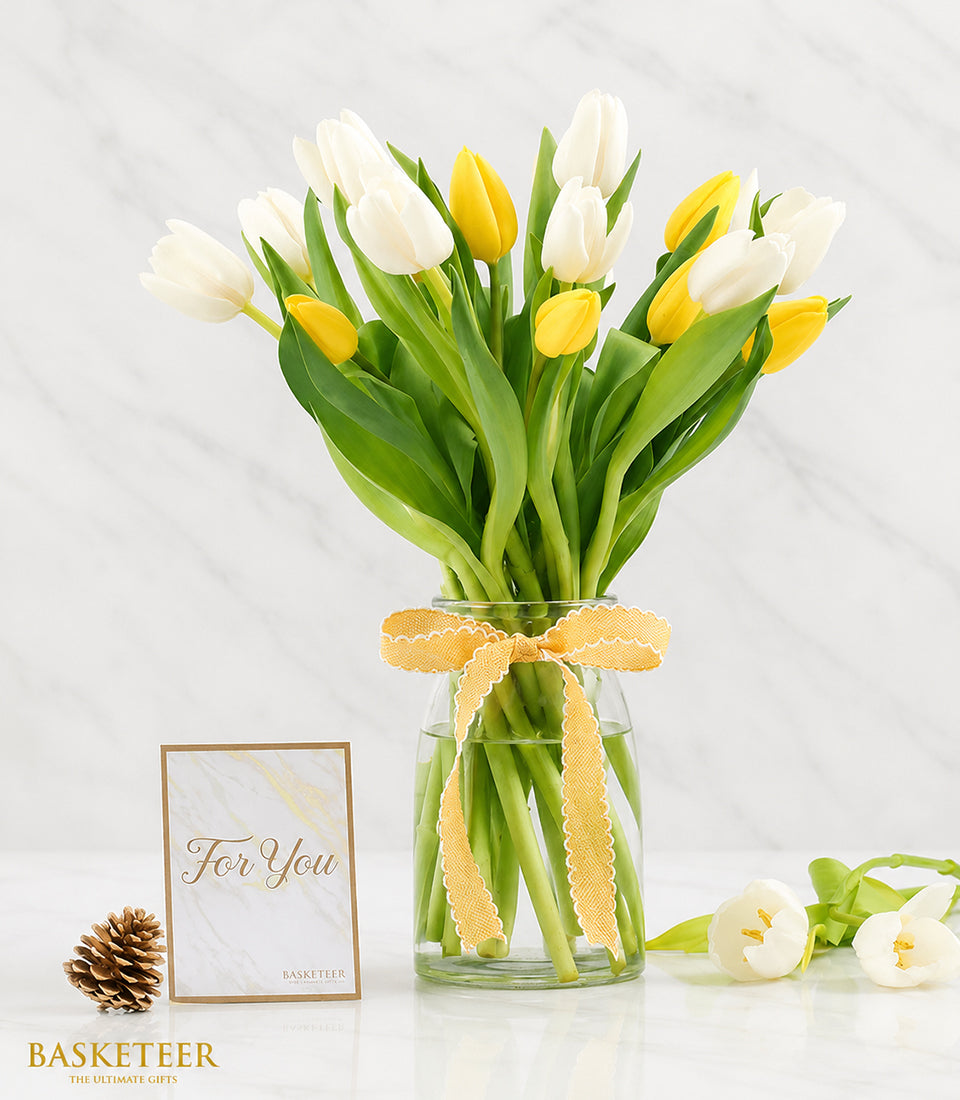 Elegant white and bright yellow tulips arranged beautifully in a clear glass vase with a delicate